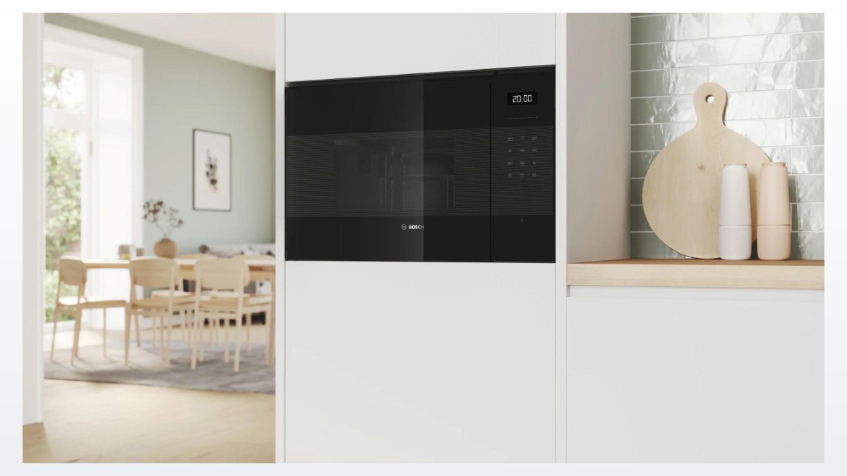 Lò vi sóng Bosch BEL554MB2 lắp âm tủ bếp trắng, bên cạnh thớt gỗ và lọ gia vị